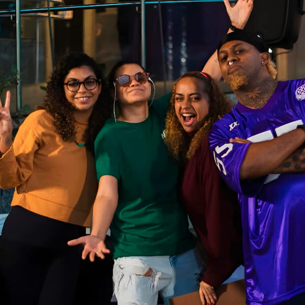 Grupo de quatro pessoas sorrindo e fazendo poses descontraídas durante o evento Slam de Surdes.