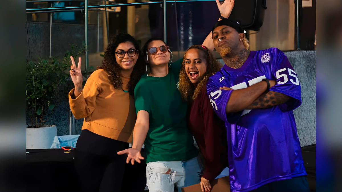 Grupo de quatro pessoas sorrindo e fazendo poses descontraídas durante o evento Slam de Surdes.