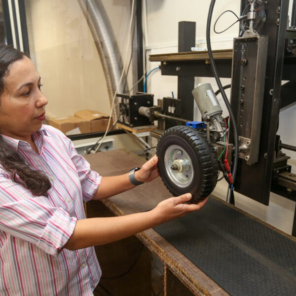Mulher manuseia kit motorizado adaptável para cadeira de rodas em laboratório de pesquisa em tecnologia assistiva. (Foto: Pedro Amatuzzi / Inova Unicamp)