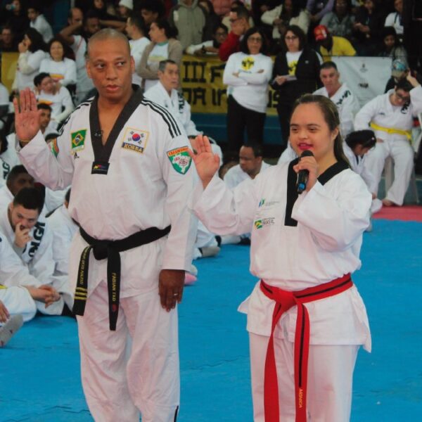Instrutor de taekwondo e jovem com trissomia 21 fazem saudação em evento do Festival Olga Kos de Inclusão Esportiva. (Créditos: Divulgação/Instituto Olga Kos)