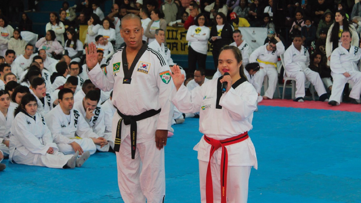 Instrutor de taekwondo e jovem com trissomia 21 fazem saudação em evento do Festival Olga Kos de Inclusão Esportiva. (Créditos: Divulgação/Instituto Olga Kos)