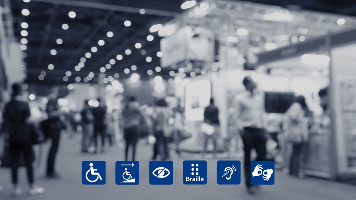 Pessoas caminhando por uma feira em ambiente fechado; no rodapé da imagem, ícones azuis representam recursos de acessibilidade em eventos, como rampa de acesso, braille e intérprete de Libras para pessoas com deficiência motora, visual e auditiva. (Créditos: Depositiphotos)