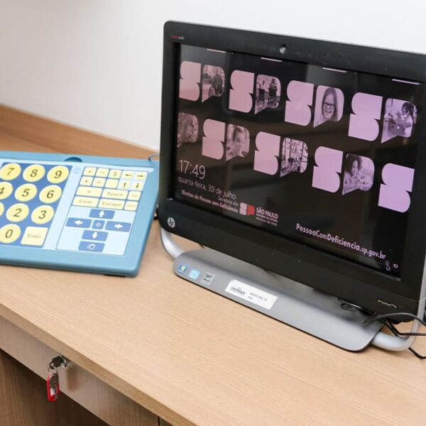 Estação de trabalho com computador e teclado acessível de teclas grandes, voltado para pessoas com deficiência, exibindo na tela o portal PessoaComDeficiencia.sp.gov.br, na Escola da Inclusão. (Foto: Acervo Univesp)