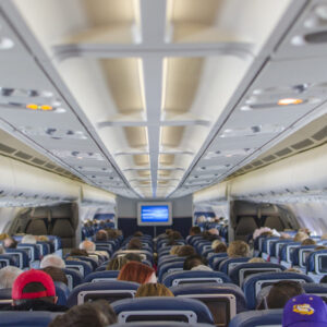Cabine de avião vista de trás, com passageiros sentados: 80% de desconto em passagens aéreas para acompanhantes de pessoas com autismo.