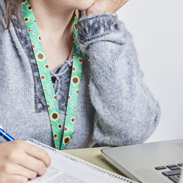 Pessoa usando cordão girassol, símbolo de deficiência oculta, como no caso de estudantes com autismo, enquanto escreve em um caderno diante de um notebook. (Créditos: Depositphotos)
