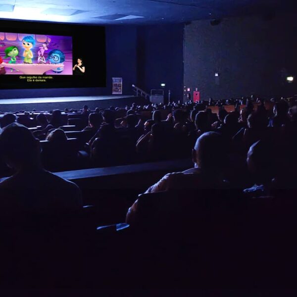 Público assiste ao filme “Divertida Mente” em cinema acessível com legenda em português e intérprete de Libras na tela. (Créditos: Divulgação)