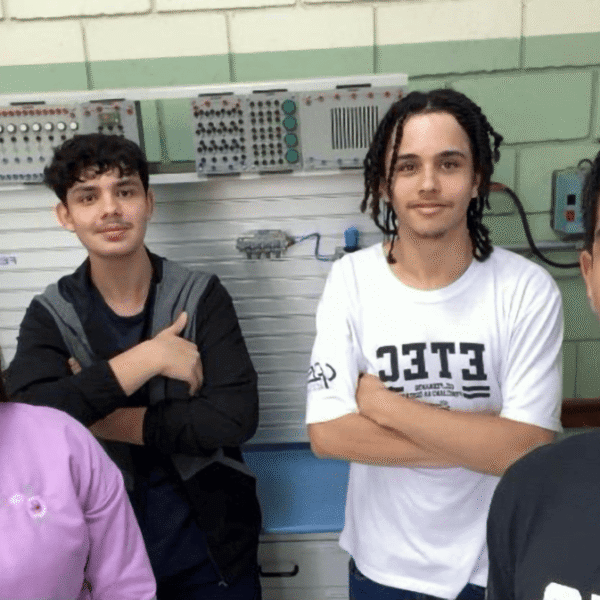 Quatro estudantes, uma mulher e três homens, no laboratório de tecnologia com painel eletrônico ao fundo. (Foto: Divulgação)
