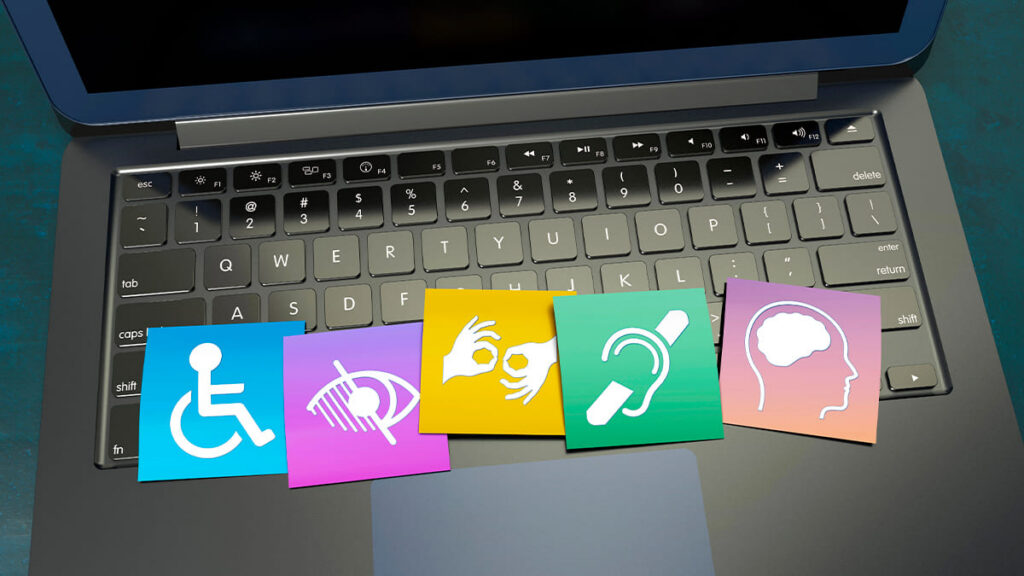 Sobre o teclado de um laptop, cinco ícones coloridos representam diferentes deficiências: física, visual, auditiva, de comunicação e intelectual. (Foto: Depositphotos)