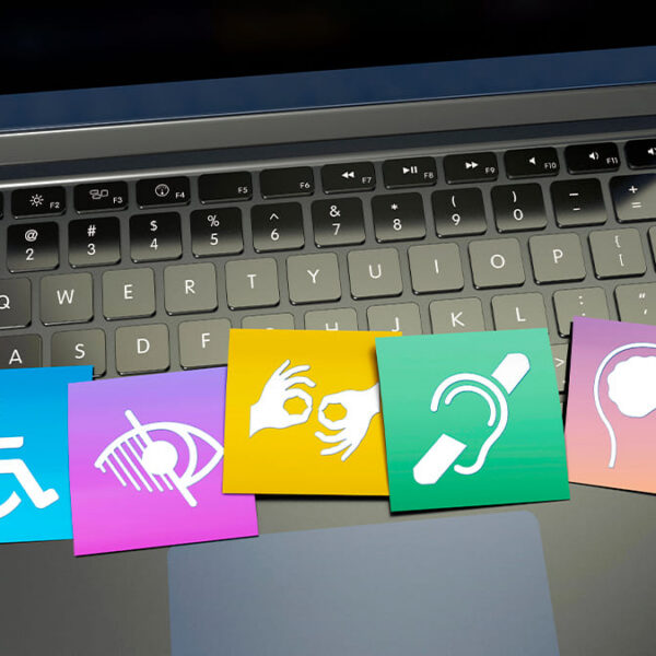 Sobre o teclado de um laptop, cinco ícones coloridos representam diferentes deficiências: física, visual, auditiva, de comunicação e intelectual. (Foto: Depositphotos)