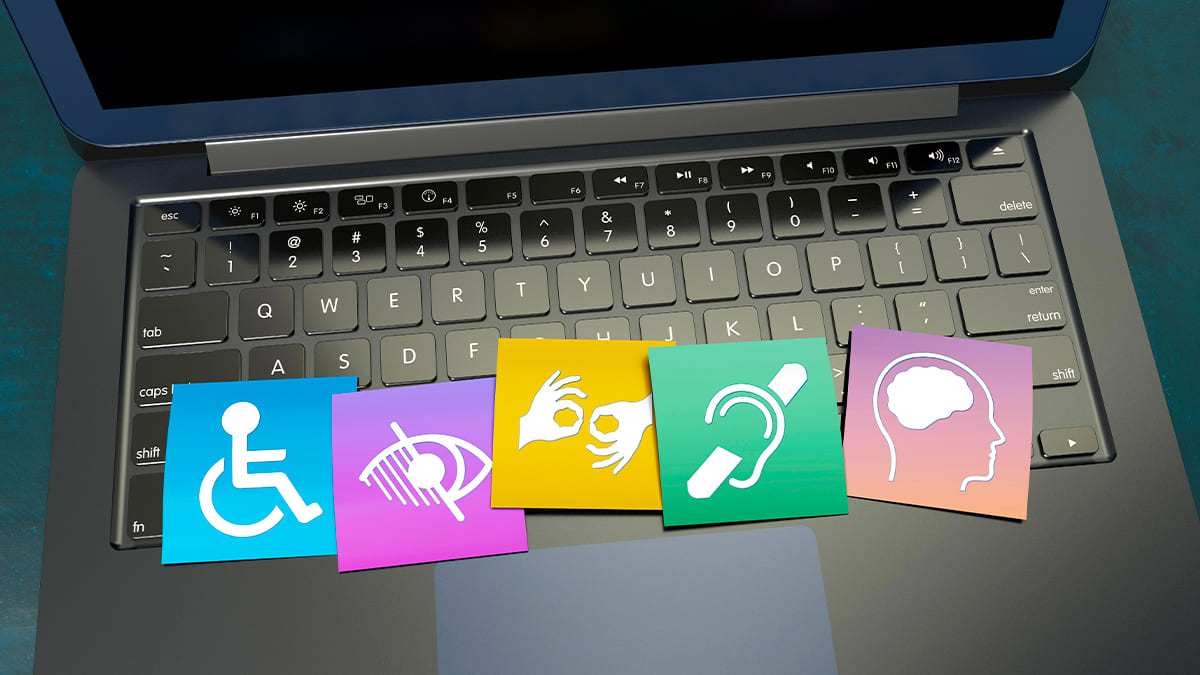 Sobre o teclado de um laptop, cinco ícones coloridos representam diferentes deficiências: física, visual, auditiva, de comunicação e intelectual. (Foto: Depositphotos)