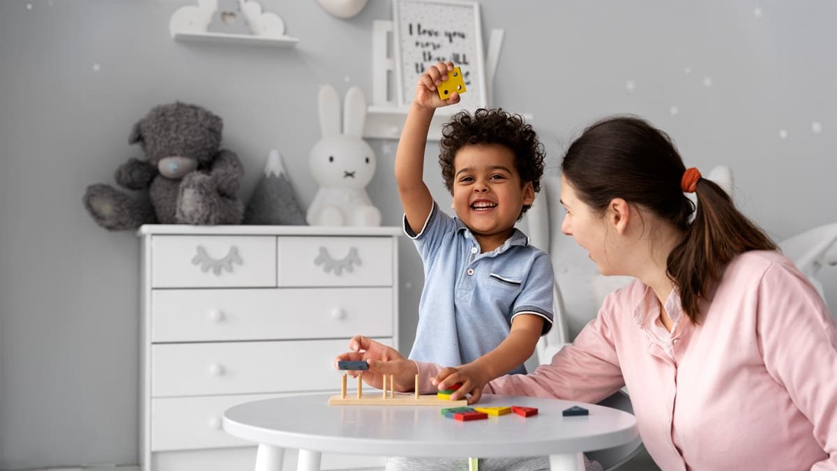 Criança e adulto brincando com blocos de construção coloridos em uma mesa branca, para abordar os mitos sobre o espectro autista.