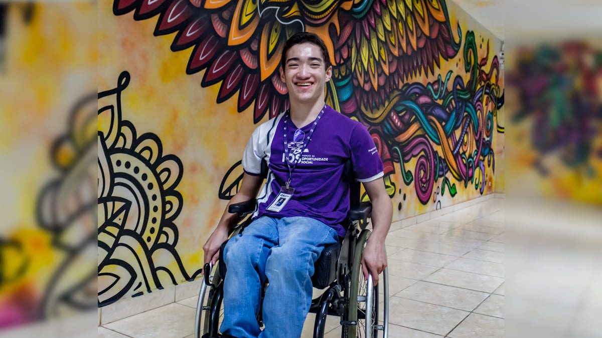 Pessoa com deficiência em frente a um mural colorido no IOS. Ilustra o programa TECPro, curso online gratuito para PcDs com bolsa de R$ 200.
